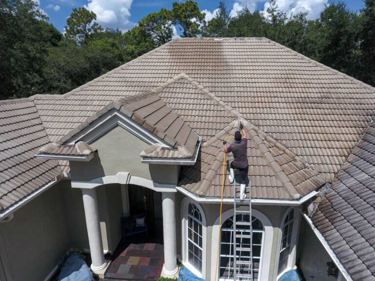 Technician applying soft wash treatment to remove roof algae on a residential home in Fort Wayne Indiana